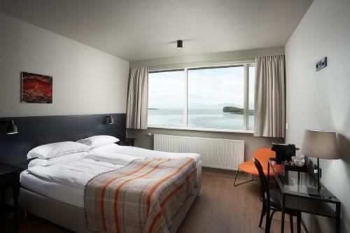 霍芬Höfn - Berjaya Iceland Hotels的一间卧室配有一张床、一张书桌和一个大窗户