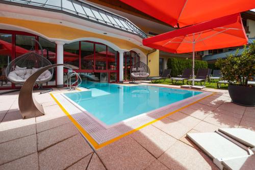 玛丽亚阿尔姆伯格乌尔斯劳霍夫温泉酒店的一座带遮阳伞的游泳池位于一座建筑旁边