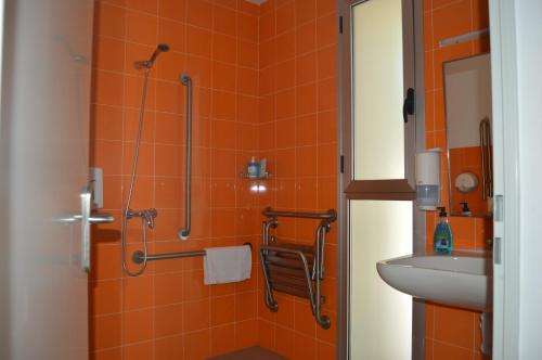Arroyo de la LuzHostel Divino Morales的橙色瓷砖浴室配有淋浴和盥洗盆