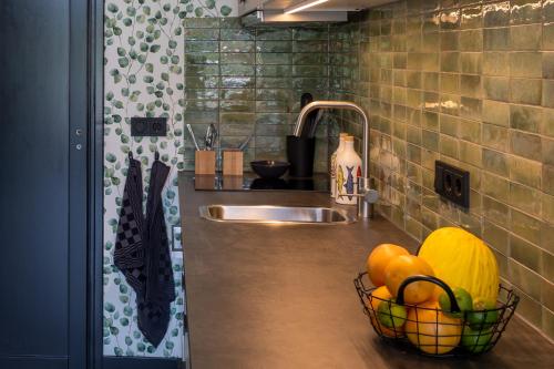 代尔登Bed & keuken De Vos的厨房柜台配有水槽和一篮水果