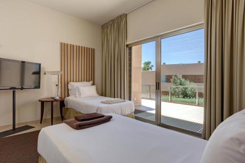 吉亚Herdade dos Salgados, Beach Villa, 3 Suites的酒店客房设有两张床和大窗户。