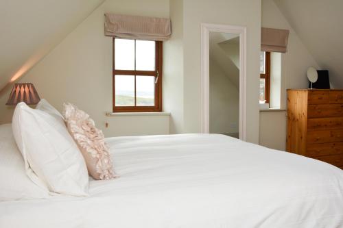 斯尼姆Beautiful stone cottage with sea views的白色的床、白色枕头和窗户
