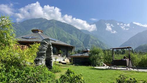 康格拉Osho Himalayas Wellness Resort的坐在房子前椅子上的女人