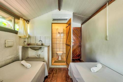伊塔卡雷Pousada Boas Ondas的客房设有两张床和一间带水槽的浴室