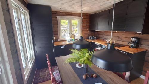 TveitenNy tømmerhytte的厨房配有黑色橱柜和木桌