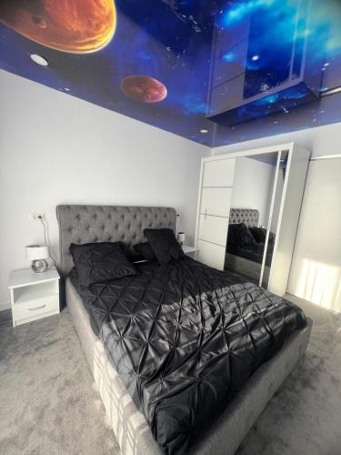 La Mara luxuri apartament的一间卧室设有一张大型黑色床,天花板上拥有行星