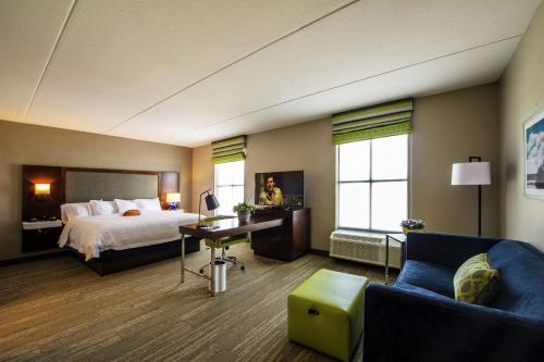 福克斯伯勒Hampton Inn & Suites/Foxborough/Mansfield的酒店客房配有一张床、一张桌子和一把椅子。