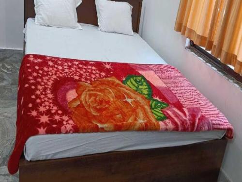 BihtaOYO Hotel K2的一张床上有红色毯子,上面有一只猫