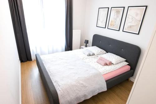 克拉科夫Nowoczesny Apartament Dąbska Arena / Parking的一间卧室配有带白色床单和粉红色枕头的床。