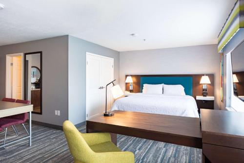 盐湖城盐湖城机场汉普顿套房酒店的酒店客房,配有一张床、一张桌子和椅子