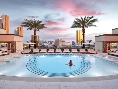 拉斯维加斯Conrad Las Vegas At Resorts World的女人在建筑物顶部的游泳池游泳