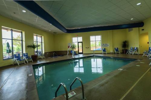 布鲁克林中心Embassy Suites by Hilton Minneapolis North的一个带蓝色椅子的健身房内的大型游泳池