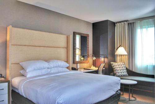 雷丁瑞丁希尔顿逸林酒店的酒店客房带一张大床和一把椅子