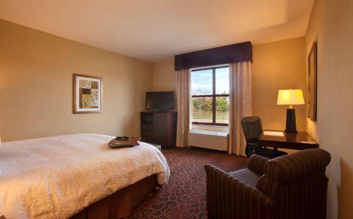 马凯特马凯特汉普顿水滨酒店的酒店的客房 - 带一张床、椅子和窗户