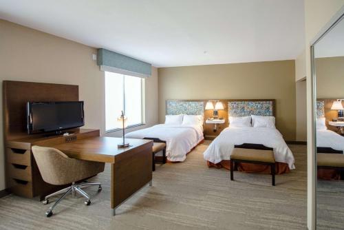 亚瑟港亚瑟港汉普顿酒店及套房的酒店客房设有两张床、一张桌子和一台电视。