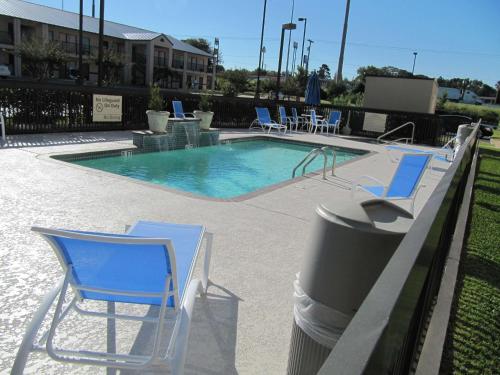 Lindale林代尔/泰勒希尔顿恒庭酒店的一个带蓝色椅子和垃圾桶的游泳池