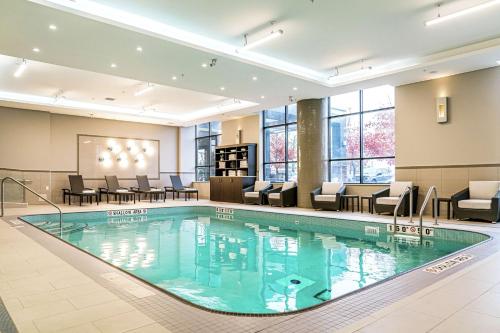 基奇纳DoubleTree by Hilton Kitchener的酒店大堂的游泳池,配有桌椅
