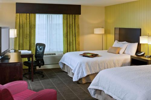 萨吉诺萨吉诺汉普顿套房酒店的酒店客房设有两张床、一张桌子和一台电视。