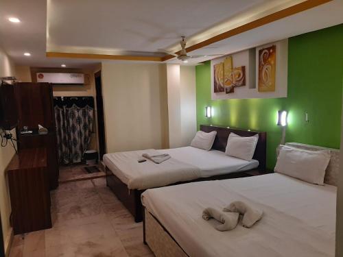 加尔各答Hotel Platinum的绿墙客房内的两张床