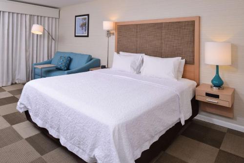 塔尔萨塔尔萨沙泉汉普顿酒店的一间卧室配有一张大床和一张蓝色椅子