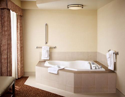 北湾诺斯贝希尔顿汉普顿酒店的浴室配有浴缸和墙上的毛巾。
