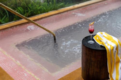 麦德林23 Hotel Medellin的热水浴池,餐桌上备有一杯葡萄酒