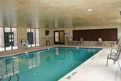 阿林顿达拉斯阿灵顿北部娱乐区汉普顿套房酒店 的大楼内带椅子的大型游泳池