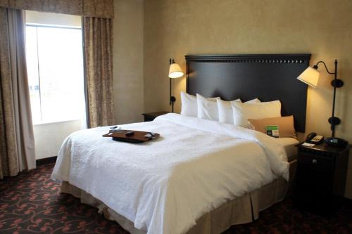 阿林顿达拉斯阿灵顿北部娱乐区汉普顿套房酒店 的酒店客房,配有一张大床,上面有行李箱