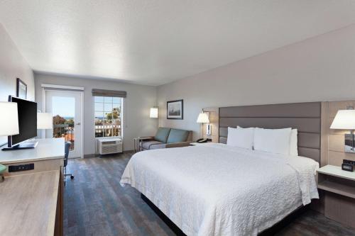 贺茂沙海滩赫莫萨比奇汉普顿套房酒店的酒店客房带一张大床和一把椅子