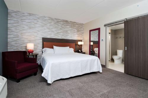 罗斯威尔Home2 Suites By Hilton Roswell, Ga的一间卧室配有一张大床和一张红色椅子