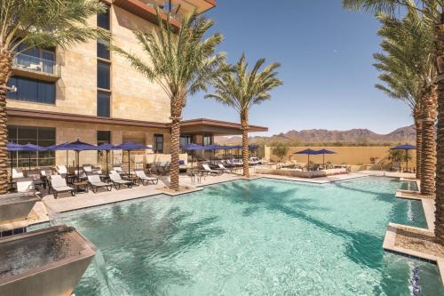 斯科茨Hilton North Scottsdale At Cavasson的棕榈树和椅子的酒店游泳池