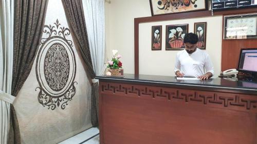卡拉奇Hotel Imperial Karachi的站在酒店房间接待台的男人