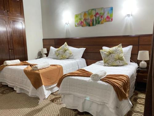 亚松森El Nogal Casa Hotel的两张位于酒店客房的床,配有毛巾