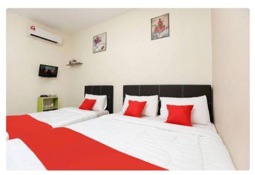 小笨珍Semerah Suites Homestay的客房内的两张床和红色枕头