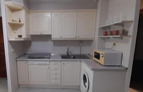 皮尔托贝加LA CASITA SERRANA的厨房配有白色橱柜、水槽和微波炉