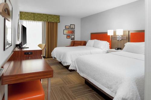 南迈阿密汉普顿酒店迈阿密/戴德兰的酒店客房设有两张床、一张桌子和一台电视。