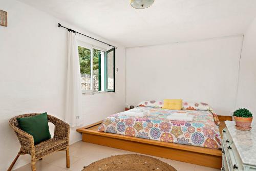 埃斯卡斯特利Casita Estancia d'en Carretero- Biniarroca的卧室配有床、椅子和窗户。