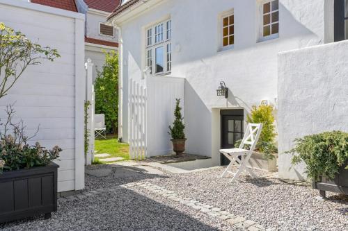 斯塔万格Apartment in Stavanger的庭院内白色的房子,配有白色椅子