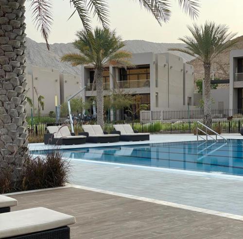 Bandar JişşahNameer bay的一个带躺椅的游泳池,棕榈树