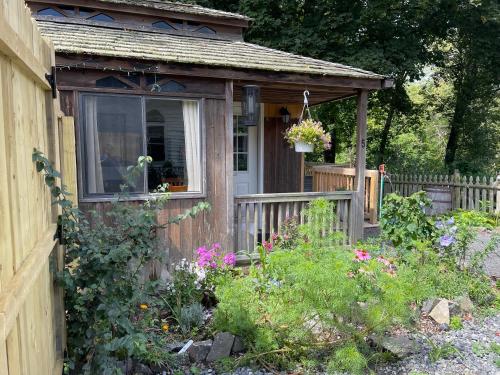 哈德逊Creekside Fantasy Inn的一个小木棚,有窗户和鲜花