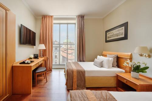 米兰Hotel Dei Cavalieri Milano Duomo的配有一张床、一张书桌和一扇窗户的酒店客房