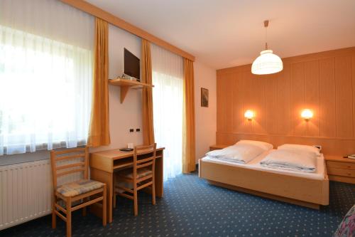 奥蒂塞伊Garni-Hotel Pichler的酒店客房配有一张床、一张书桌、一张床和一张书桌。