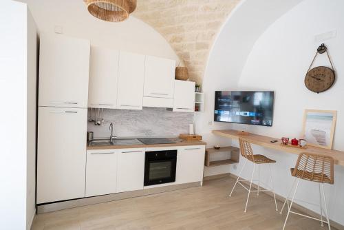 曼弗雷多尼亚Adelmarì Casa Vacanze的厨房配有白色橱柜和桌椅