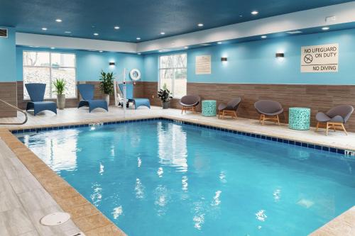 新斯坦顿Hampton Inn & Suites Pittsburgh New Stanton PA的游泳池位于酒店带蓝色墙壁和椅子的房间内