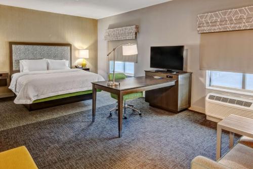 圣何塞Hampton Inn & Suites San Jose Airport的酒店客房配有一张床和一张书桌及一台电视