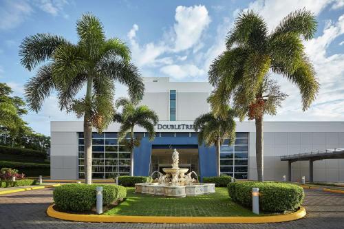 马那瓜Hilton DoubleTree by Hilton Managua的喷泉前有棕榈树的建筑