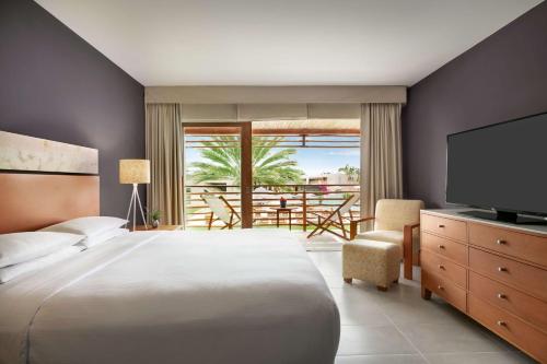 帕拉卡斯The Legend Paracas Resort的一间卧室配有一张床、一台电视和一个阳台