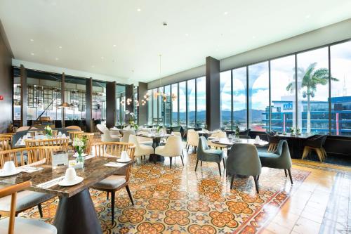 圣何塞哥斯达黎加格兰希尔顿Curio Collection酒店的餐厅设有桌椅和大窗户。