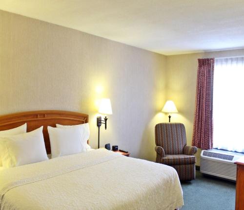 萨尔蒂约希尔顿萨尔蒂约佐娜机场汉普顿酒店的配有一张床和一把椅子的酒店客房