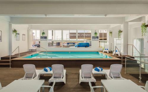 提华纳提华纳汉普顿希尔顿酒店的一个带椅子的游泳池和一个游泳池